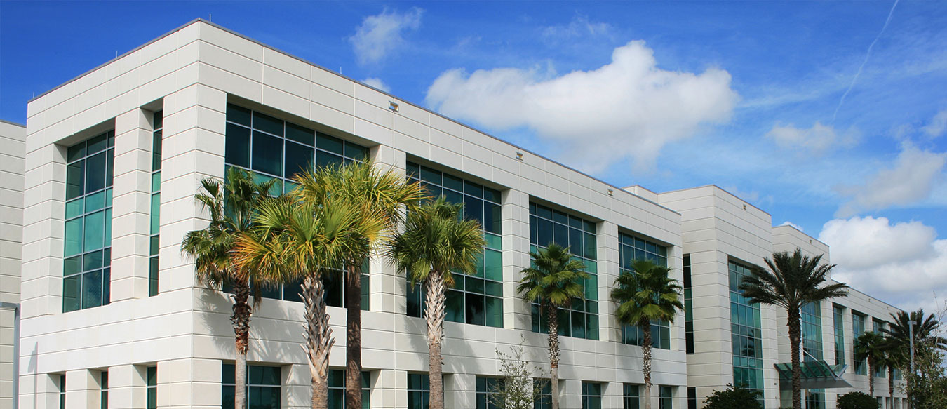 Commercial building on sunny day in California with palm trees out front, large glass windows.