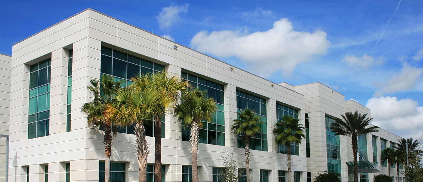 Commercial building on sunny day in California with palm trees out front, large glass windows. 